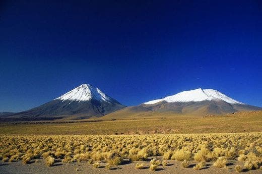 HR001279 White-peaked volcanos rise from the plains of the Atacama Desert under deep blue skies. The Atacama is the driest desert in the world.