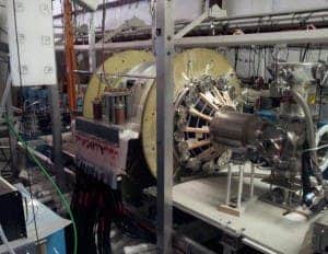 The fusion driven rocket test chamber at the UW Plasma Dynamics Lab in Redmond. The green vacuum chamber is surrounded by two large, high-strength aluminum magnets. These magnets are powered by energy-storage capacitors through the many cables connected to them. (c) University of Washington