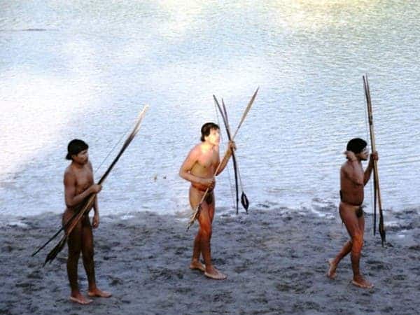 Three members of a recently contacted tribe walk with weapons in hand in Brazil. (c) FUNAI