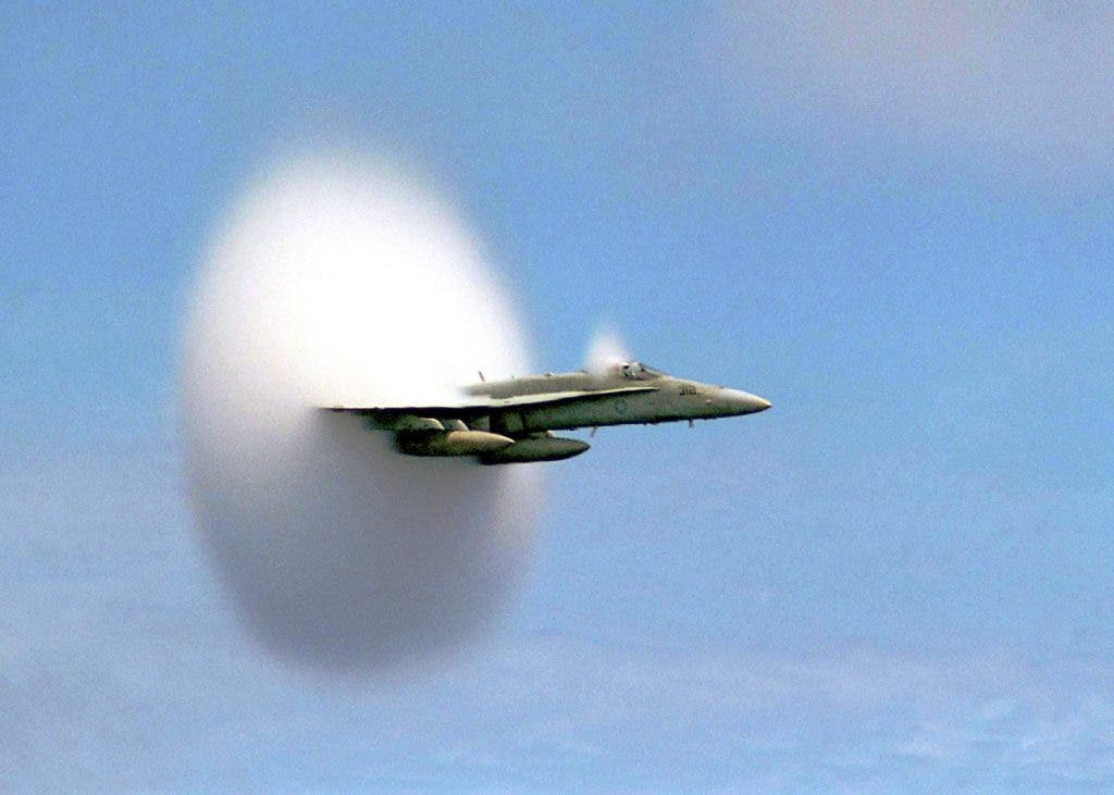 A fighter jet photographed in the midst of a sonic boom. The plane travels faster than the sound it emits. As it pieces the sound wave, a roaring boom commences. Credit: YouTube capture.