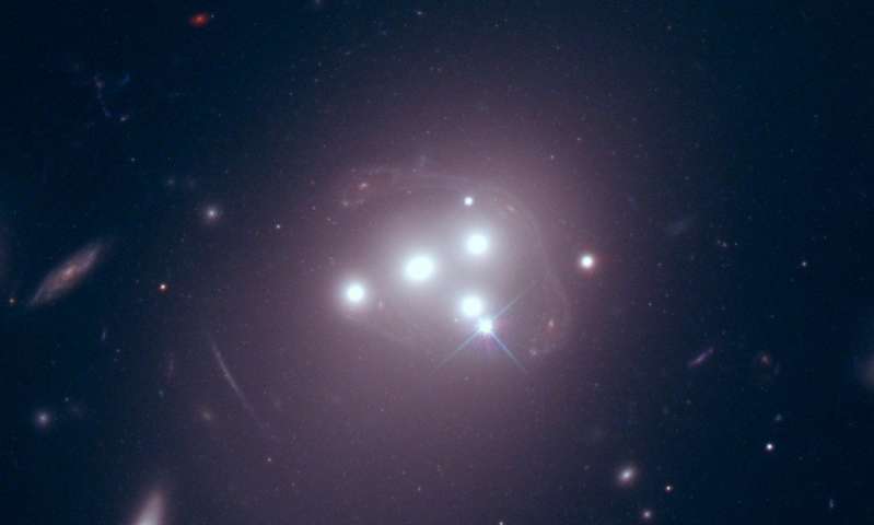 These are four giant galaxies located at the center of the cluster Abell 3827, as seen by the Hubble Space Telescope. The distorted image of a more distant galaxy behind the cluster is faintly visible, wrapped around the four galaxies. Credit: NASA/ESA/Richard Massey. Credit: Durham University.