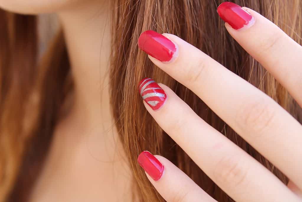 Closeup of woman's hand with red painted nails.