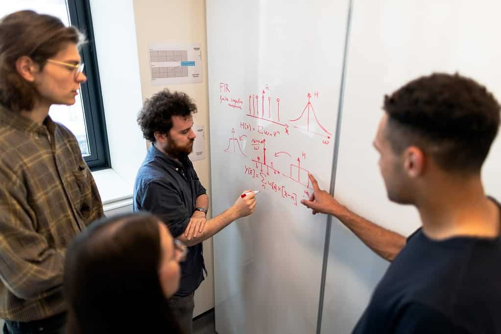 students working on mathematics at a whiteboard
