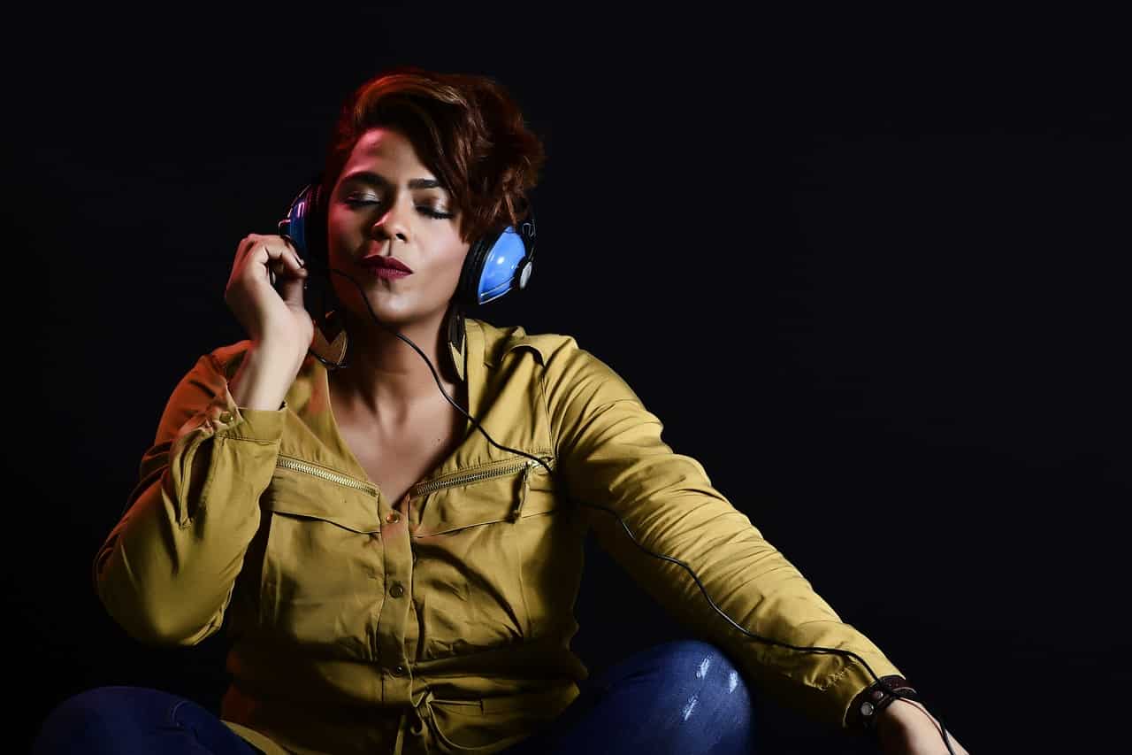 Black woman listening to music on headphones with her eyes closed.